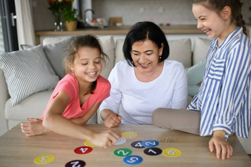 A grandmother playing a card game with two kids around 9 years old. 